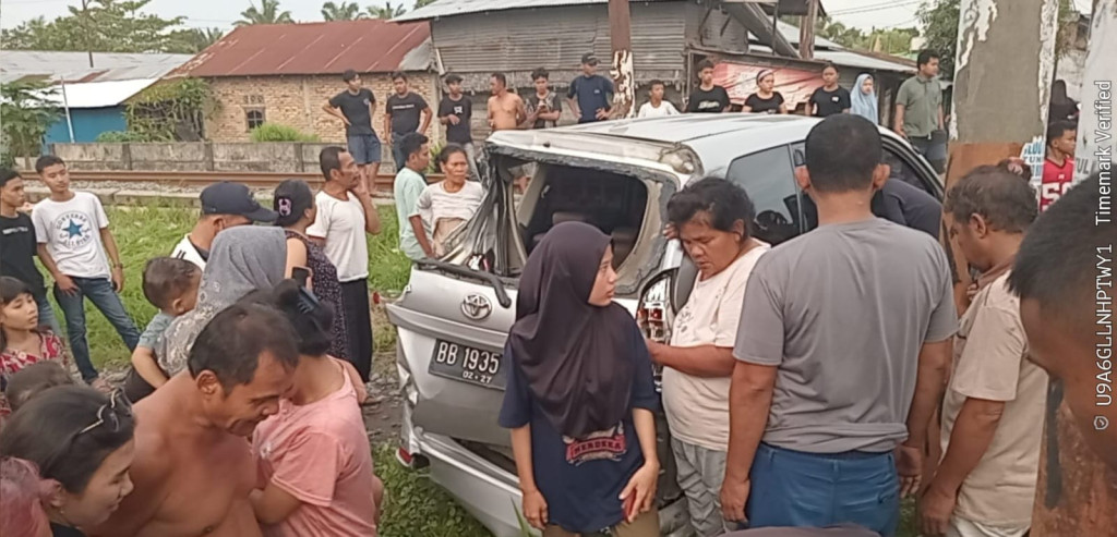 Kereta Api Temper Minibus di Perlintasan Palang Pintu di Medan